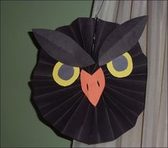 a black paper owl with yellow eyes and an orange beak on it's head