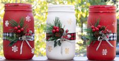 three mason jars decorated with holly and pine cones