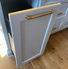 an open cabinet door in a kitchen with wood floors and white cupboards on either side