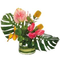 a vase filled with lots of flowers and greenery on top of a white surface