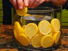 someone is squeezing lemons into a glass bowl