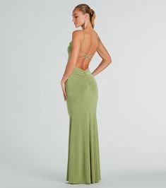 a woman in a long green dress with her back turned to the camera, looking down