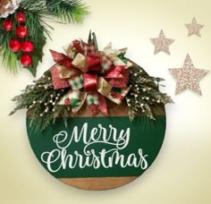 a merry christmas sign hanging on the side of a wooden wall with decorations around it