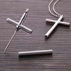 two cross pendants sitting on top of a wooden table