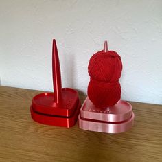 a red ball of yarn sitting on top of a wooden table next to a crochet hook