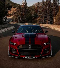 the front end of a red sports car on a road with trees in the background