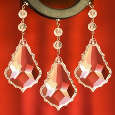 two pairs of earrings hanging from the side of a red wall with a clock in the background