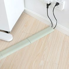 an electrical outlet plugged into the wall next to a white cabinet and wooden floor