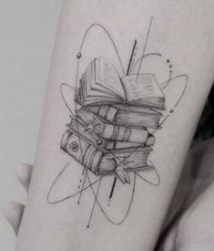 a person with a tattoo on their arm that has books stacked on top of each other