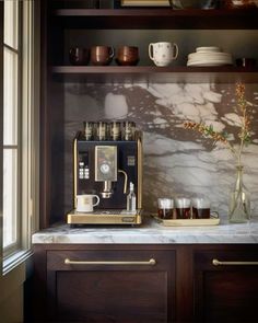 an espresso machine sitting on top of a counter next to some cups and saucers