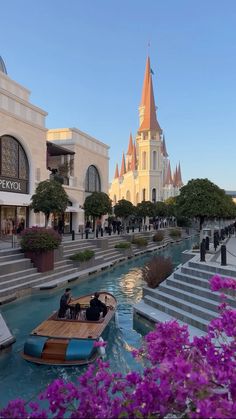 a small boat floating on top of a river next to a tall building with spires