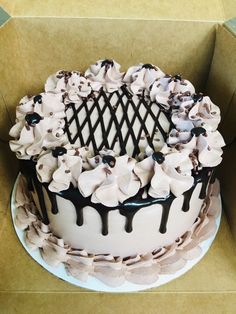 a white cake with chocolate icing and flowers on top in a cardboard box,