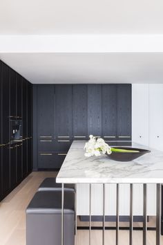 a kitchen with black cabinets and marble counter tops, along with a white center island