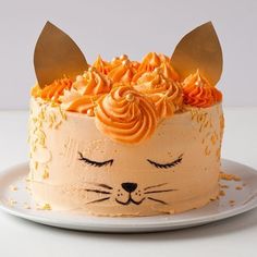 a cat cake with orange frosting and gold sprinkles on the top