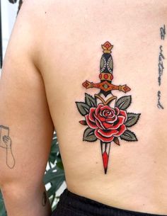 a woman with a rose and dagger tattoo on her back