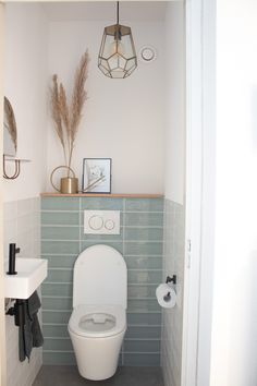 a white toilet sitting inside of a bathroom next to a wall mounted light above it