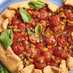 a pizza with tomatoes, corn and basil on it