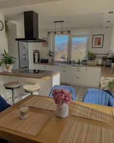 a vase with flowers sitting on top of a wooden table in a kitchen next to a window