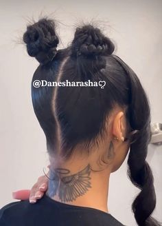 the back of a woman's head with two buns and tattoos on her neck