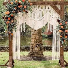 an outdoor wedding ceremony setup with macrame and flowers on the arbor, surrounded by greenery