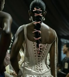 the back of a woman's dress with pink ribbons tied to her neck and shoulders