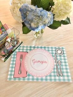 there is a place mat, fork and knife on the table next to some flowers