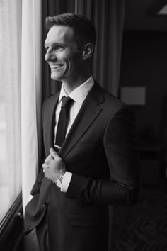 a man in a suit and tie standing next to a window