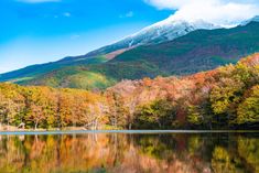 the mountains are covered in snow and fall foliage, with trees reflecting in the water