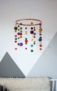 the diy felt ball baby mobile is hanging on the wall next to a crib