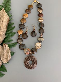 Look your best wearing this unique chunky stone necklace!  The handmade, one of a kind jewelry set consists of an 18 inch necklace and matching earrings.  The necklace has round, flat, smooth 20 mm, bronze zebra Jasper stones that are separated with petite gold beads.  A floral, 1.5 inch, copper donut pendant is the focal point of the necklace.  The necklace closes securely with a small, gold tone, round box clasp.  The 2 inch dangle earrings feature the same beads and simple, gold-filled ear wires.  The set will be a welcome addition to your jewelry collection or will make a great gift idea for someone. This jewelry set is designed and handmade by me, Sharon, of Blonde Peach Jewelry. It will arrive in an attractive organza bag that is great for storage or gift giving. Feel free to contact Earthy Brown Round Jewelry, Earthy Bronze Round Bead Jewelry, Earthy Bronze Round Beads Jewelry, Earthy Bronze Jewelry With Round Beads, Brown Copper Round Jewelry, Earthy Bronze Beaded Jewelry, Earthy Brown Round Pendant Jewelry, Nature-inspired Brown Round Bead Jewelry, Nature-inspired Brown Round Jewelry