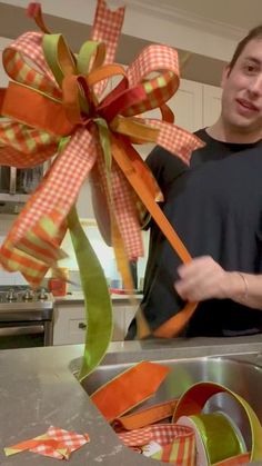 a man standing next to a kitchen sink holding a ribbon in front of him and looking at the camera