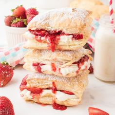 strawberry shortcakes stacked on top of each other with strawberries and milk in the background