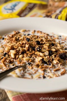 a white plate topped with granola and raisins next to a bag of cereal