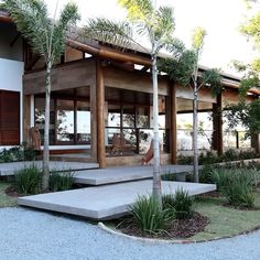 a modern house with trees in front of it and concrete steps leading up to the entrance