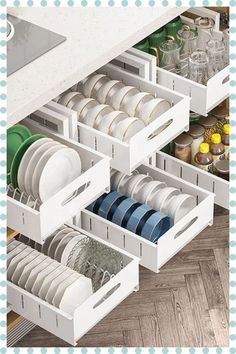 an open drawer filled with dishes and plates on top of a wooden floor next to a counter