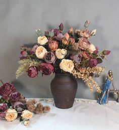 a vase filled with lots of flowers sitting on top of a white cloth covered table