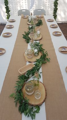 a long table is set up with place settings and greenery on the runneres