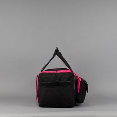 a black and pink duffel bag sitting on top of a gray surface with a white background