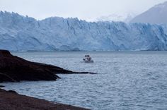 a boat is in the water near some mountains and icebergs that are behind it