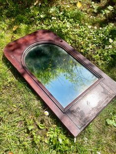 a mirror sitting on the ground in some grass