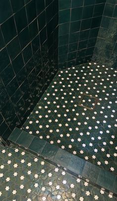 a green tiled bathroom with white crosses on the floor