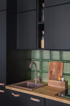 a kitchen with black cabinets and green glass tiles on the backsplash is shown