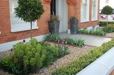 a brick building with plants and flowers in the front yard