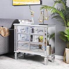 a living room with a grey couch and a silver mirrored cabinet in front of a gray wall