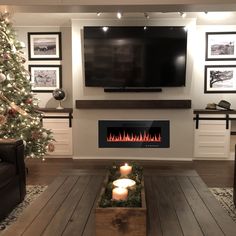 a living room with a christmas tree, fireplace and television on the wall in front of it