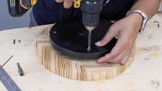 a person is using a drill to cut wood with a circular tool on a table