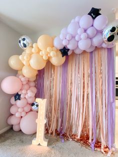 balloons and streamers are hanging from the ceiling in front of a birthday party backdrop