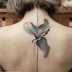 the back of a woman's neck is covered with watercolors and has a flower tattoo on it