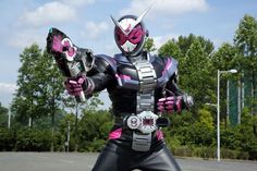 a man dressed in black and pink is holding two metal arms while standing on the street