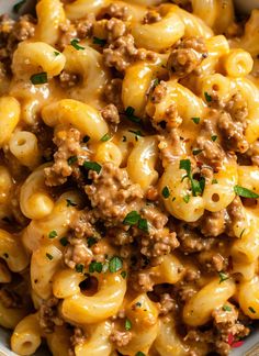 a white bowl filled with macaroni and cheese covered in ground beef, parsley